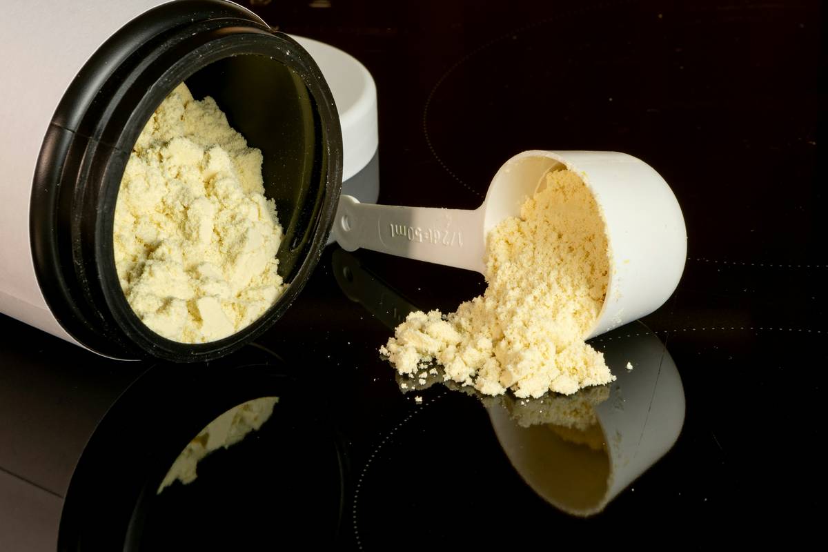 Vanilla protein supplement jar and scoop, muscle recovery and fitness.